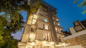 A multi-story building with balconies, a stone wall, and a staircase. - Alara by Alaya Stays 4-BHK Apartment (Kanayannur)