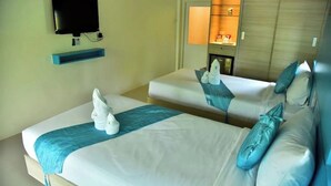 Habitación de hotel con dos camas, televisión, minibar y armario de madera.