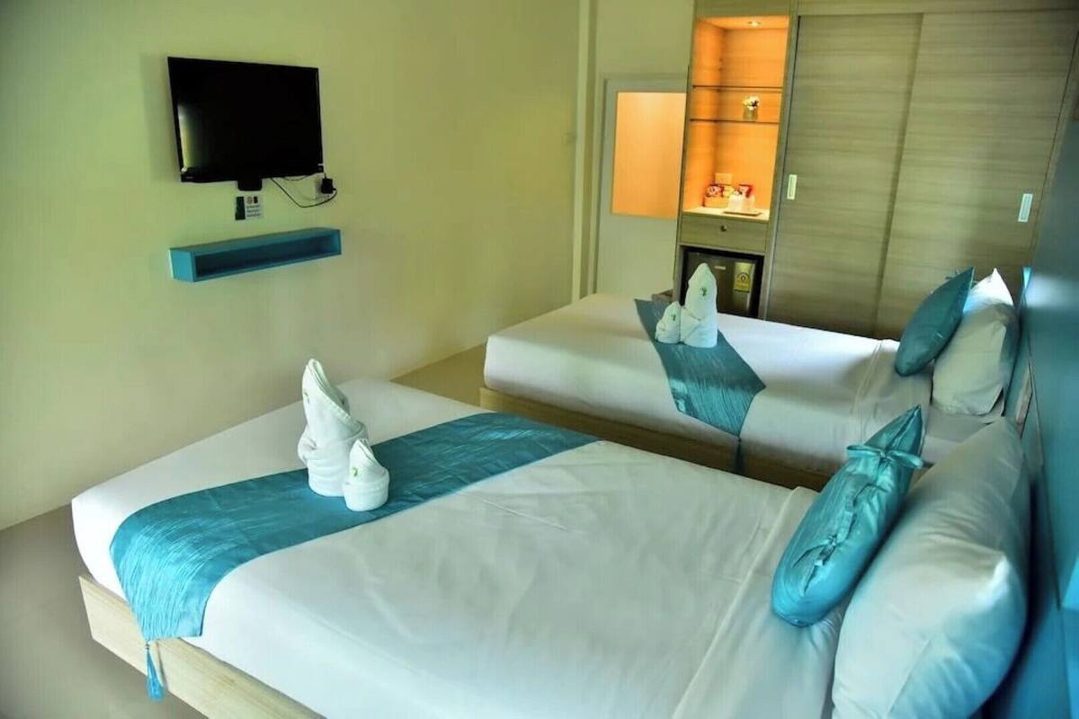 Habitación de hotel con dos camas, televisión, minibar y armario de madera.
