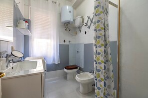 Une salle de bain équipée d’un lavabo, de toilettes, d’un bidet et d’un rideau de douche.