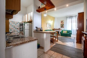 Una cocina con encimeras de granito, horno empotrado y una zona de comedor con sofá verde.