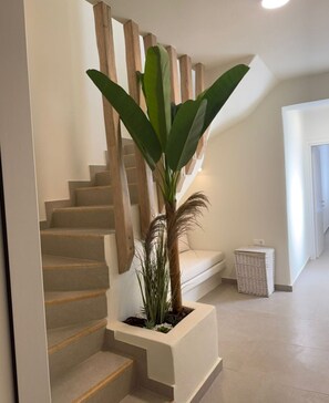 Una escalera con barandillas de madera, una planta en maceta y una cesta de mimbre.