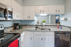 A kitchen with white cabinets, a stainless steel microwave, a stove, a sink, and a dishwasher. - Near Expressways! Cozy Dallas Condo w/ Workspace (Dallas)