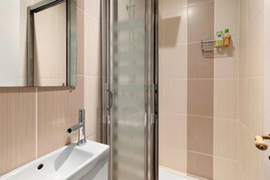 A bathroom with a glass shower enclosure, a sink, and a mirror. - Apartment “Hortensia” with Private Terrace and Garden (Sarlat-la-Canéda)