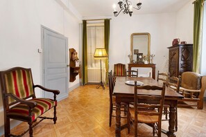 A dining area with a wooden table, chairs, a lamp, and a mirror. - Apartment “Hortensia” with Private Terrace and Garden (Sarlat-la-Canéda)