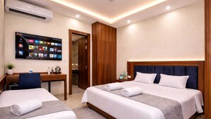 Habitació d'hotel amb dos llits, una taula de treball, un televisor i un armari.