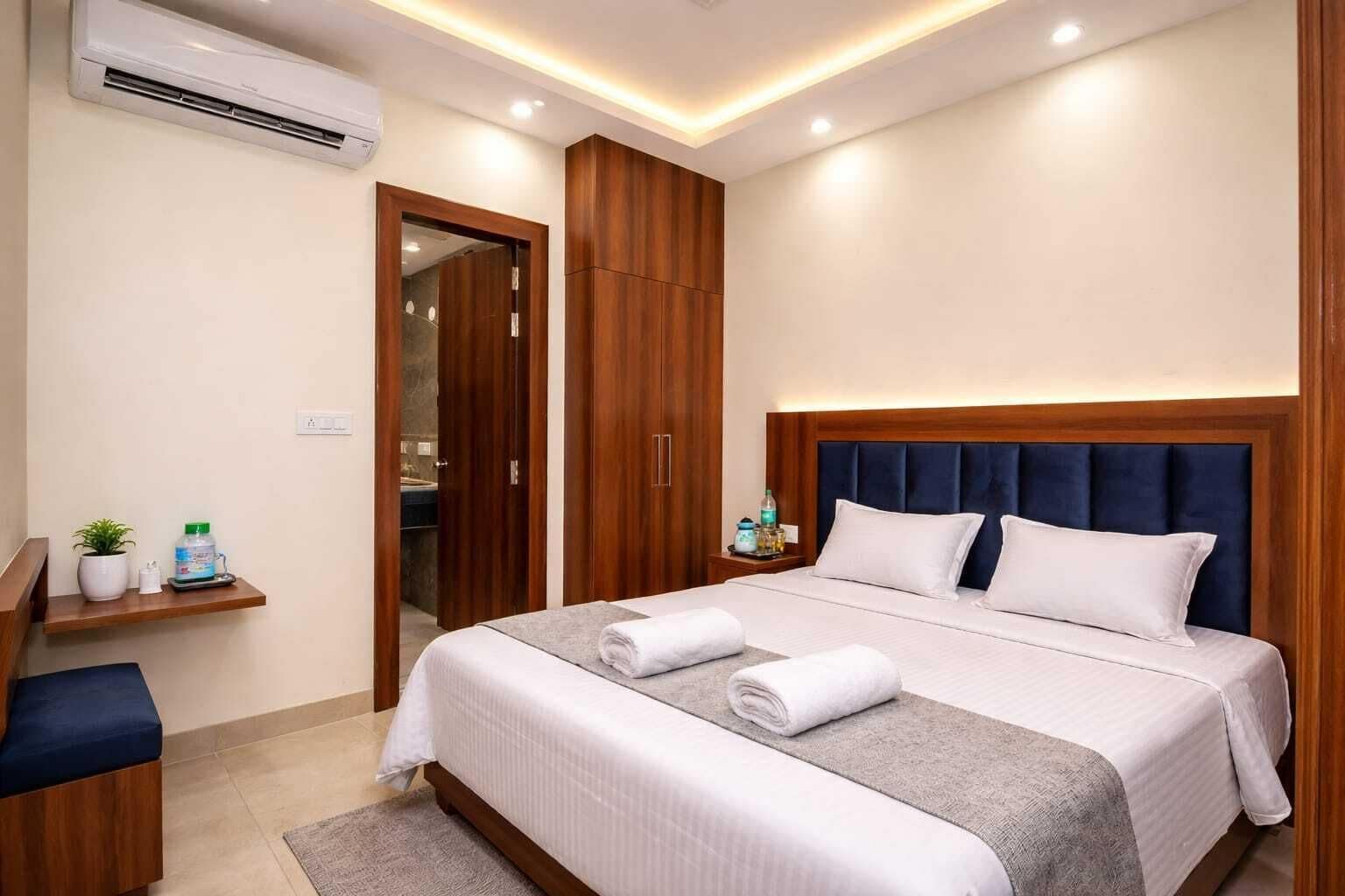 Une chambre d’hôtel comprenant un lit, des tables de chevet, un bureau, une chaise, une armoire et un appareil de climatisation.