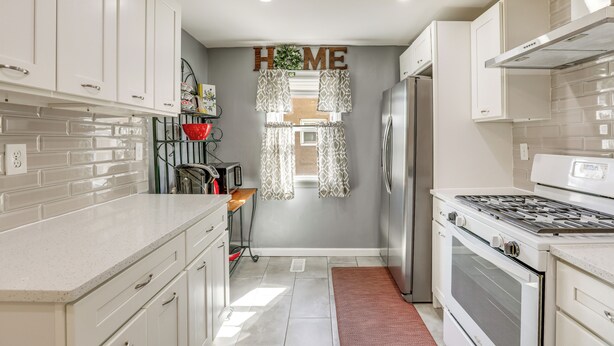 A kitchen with white cabinets, a stainless steel refrigerator, a stove, and a 'HOME' sign on the wall. - 1 Mi to NYC Train & Arts District: Rahway Escape (Rahway)