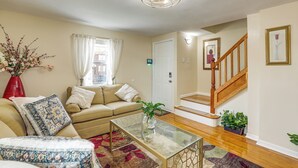 A living room with a sofa, a glass coffee table, a red vase, a staircase, and a door. - 1 Mi to NYC Train & Arts District: Rahway Escape (Rahway)