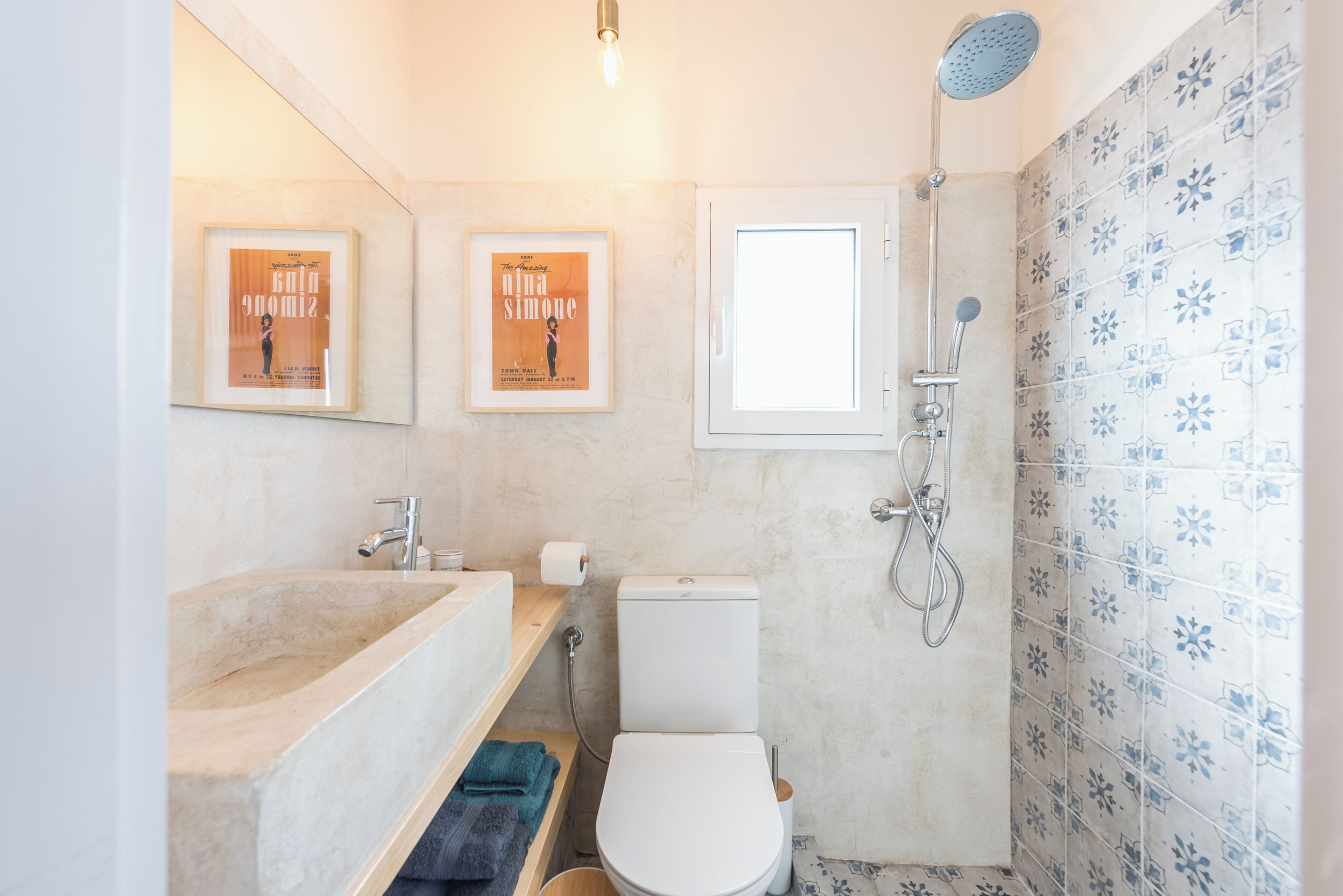Une salle de bain avec une baignoire, des toilettes et une douche. Il y a des tableaux encadrés au mur et une fenêtre.