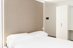 Ett hotellrum med en säng, en garderob och en väggmonterad ljusströmbrytare.