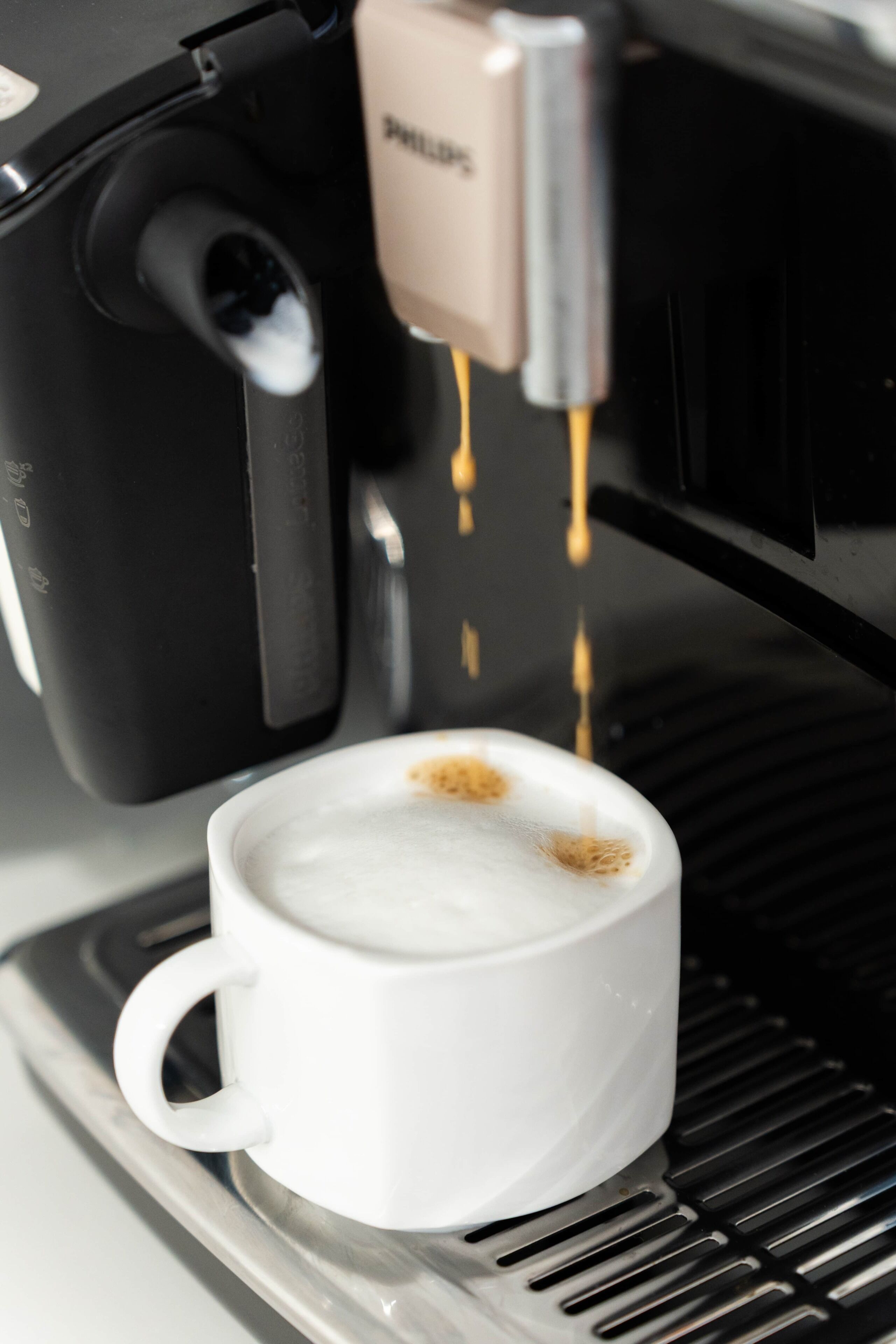 A coffee machine dispensing coffee into a white cup.