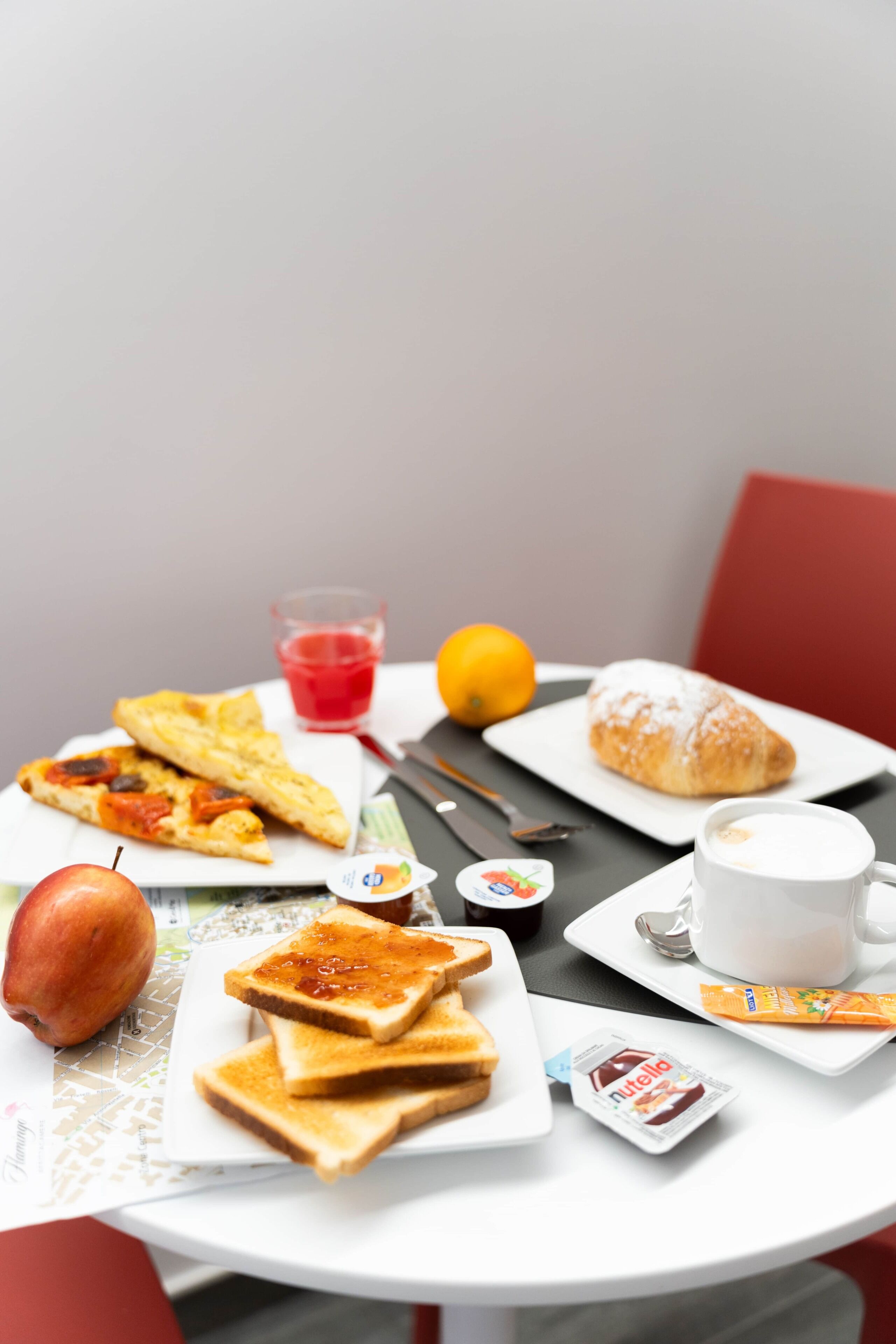 A table with breakfast items including toast, croissant, apple, juice, and a cup of coffee.
