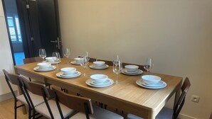 Une table à manger dressée avec de l’argenterie blanche et des verres, entourée de chaises dotées d’assises rembourrées.
