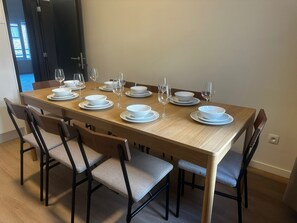 Een eettafel gedekt met witte borden en glazen, omringd door stoelen met beklede zitplaatsen.