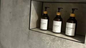 Une étagère avec trois bouteilles de gel douche, de shampoing et d’après-shampoing.