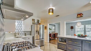 A modern kitchen with a gas stove, stainless steel appliances, and a large island. - Family + Pet Friendly: Fort Worth Home Near TCU! (Fort Worth)