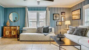 A living room with a sofa, a coffee table, a cabinet, and a ceiling fan. - Family + Pet Friendly: Fort Worth Home Near TCU! (Fort Worth)