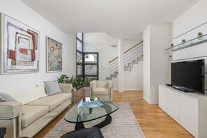 A modern living room with a glass coffee table, a sofa, a TV, and artwork on the walls. - RM Grande Villa – Left Wing (Rovinj)