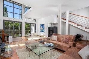 Ein geräumiges Wohnzimmer mit einem Glastisch, einer Couch und einem Kamin.