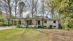 Een gelijkvloers huis met een overdekte veranda, voortuin en oprit.