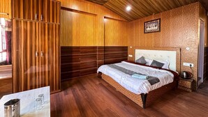A bedroom with a wooden ceiling, a large bed, a wardrobe, and a small bedside table. - Kufri Paradise Villa By Mountain Bee (Theog)