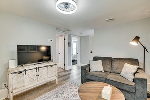 Ein Wohnzimmer mit Fernseher, Sofa, Couchtisch und einem gemusterten Teppich.