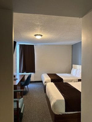 Una habitación de hotel con dos camas, un escritorio y una silla.