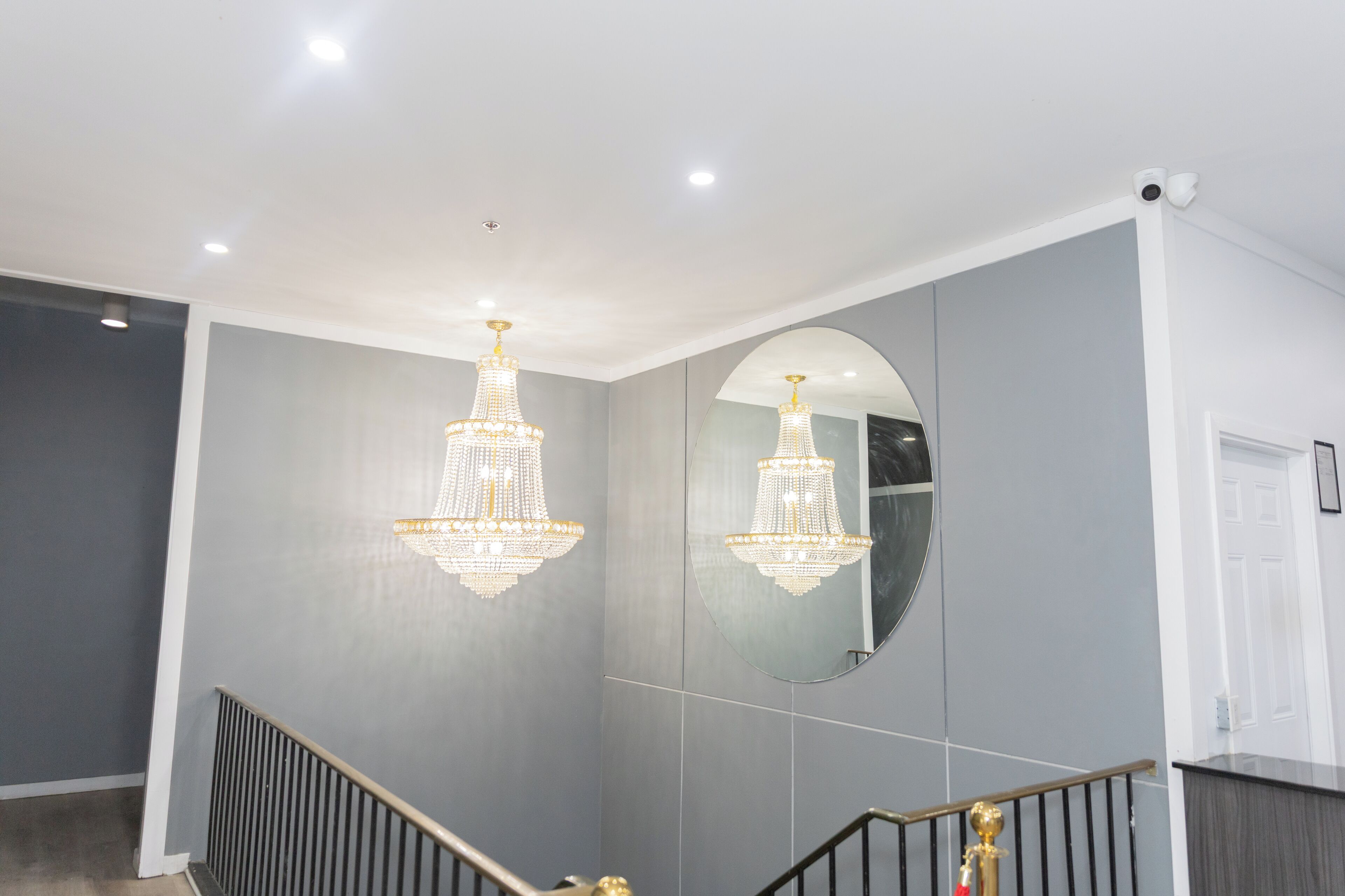 Ein modernes Interieur mit Treppe, Kronleuchtern, einem großen Spiegel und einer Tür.