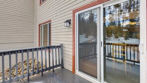 A covered deck with a railing, a sliding glass door, and a stone ledge. - Condo 3 Mi to Winter Park Resort: Community Perks! (Winter Park)