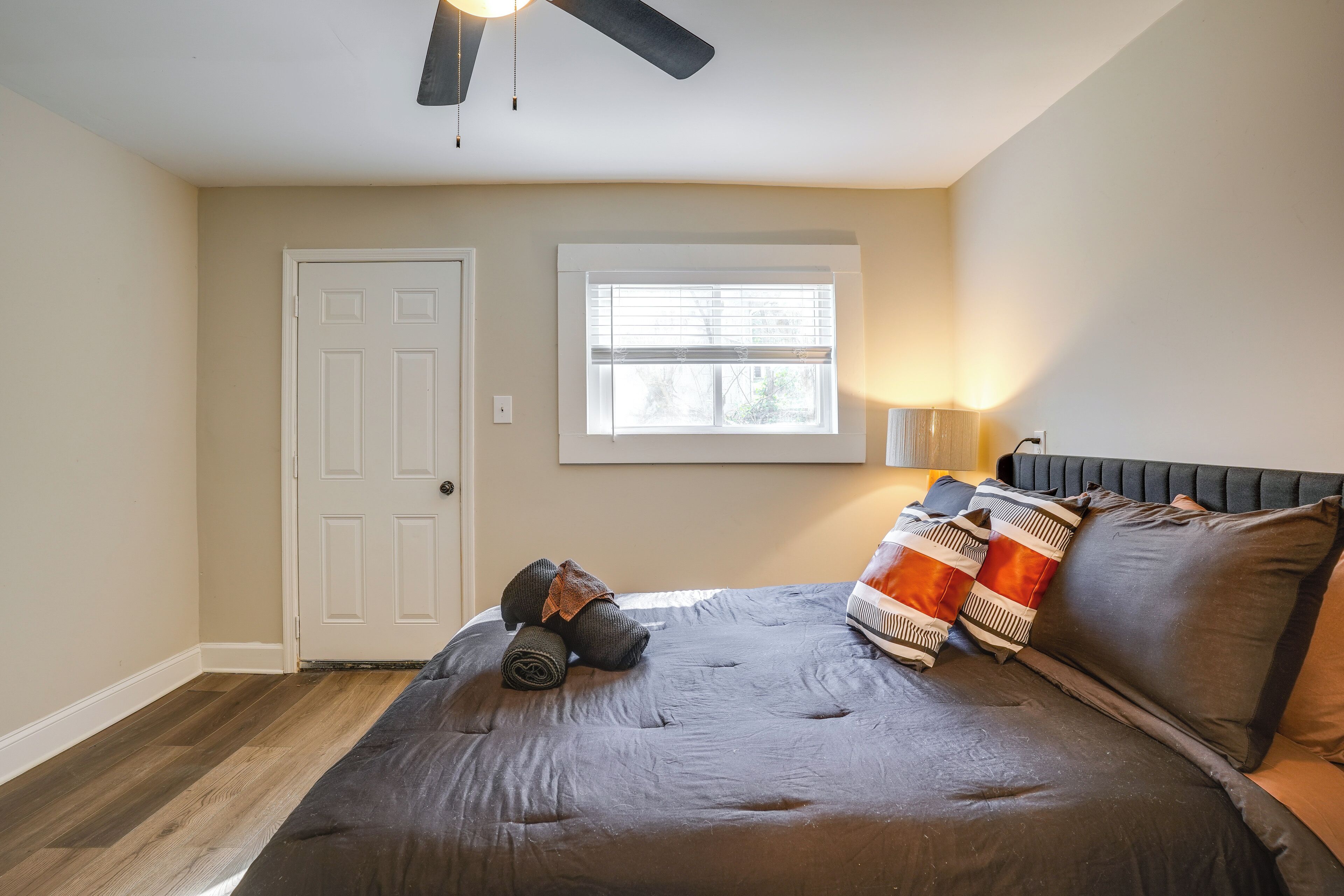 A bedroom with a bed, a ceiling fan, a window, and a door.