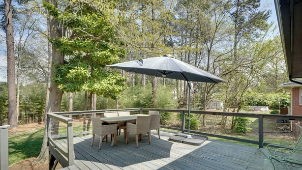 A wooden deck with a table and chairs, surrounded by trees. - Deck & Patio! Walkable Downtown Cary Home (Cary)