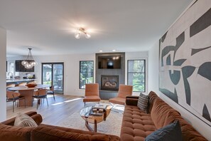 A modern living room with a fireplace, a dining area, and a large abstract painting on the wall. - 3 Mi to Beach From 'The Harbor Collective' (New Buffalo)