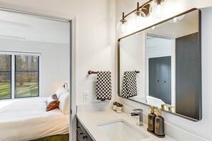 A modern bathroom with a large mirror, a white sink, and a bed with a view of the outdoors. - 3 Mi to Beach From 'The Harbor Collective' (New Buffalo)