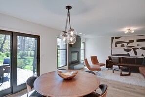 A modern living room with a round wooden table, a fireplace, and a large abstract painting on the wall. - 3 Mi to Beach From 'The Harbor Collective' (New Buffalo)