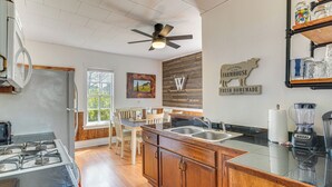 Cucina con piano cottura a gas, pensili in legno, lavandino e ventilatore a soffitto.