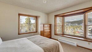A bedroom with a bed, a dresser, and two windows with blinds. - Mtn Base w/ Hot Tub Access Near Winter Park Resort (Winter Park)