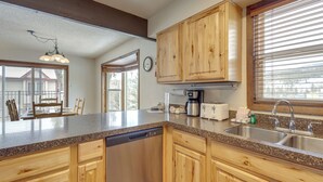A kitchen with wooden cabinets, a dishwasher, a coffee maker, and a sink. - Mtn Base w/ Hot Tub Access Near Winter Park Resort (Winter Park)
