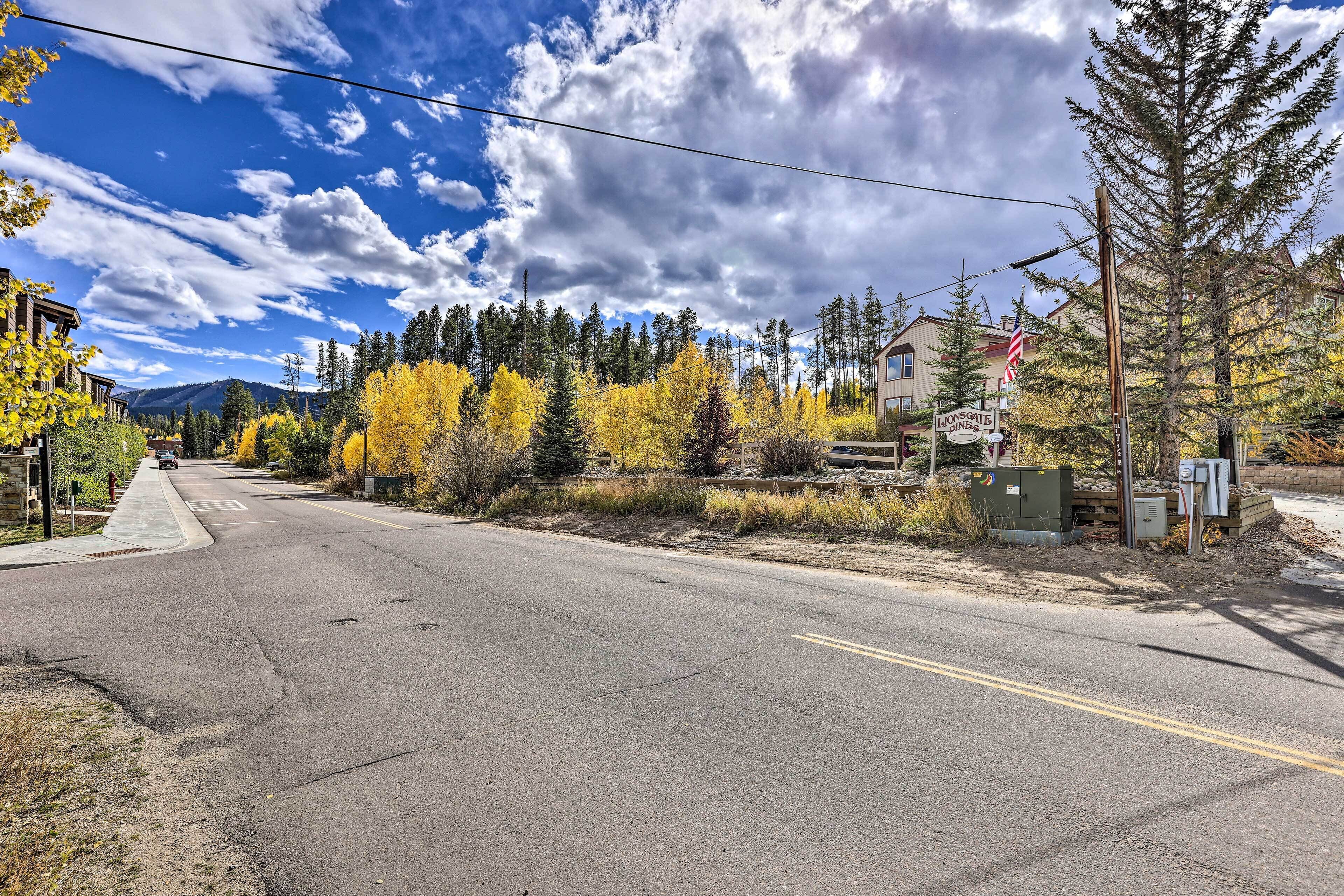 A road with a sign for Lionsgate Inn, surrounded by autumn foliage and a clear sky.