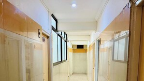 Un pasillo con puertas a ambos lados, suelo de baldosas y una lámpara en el techo.