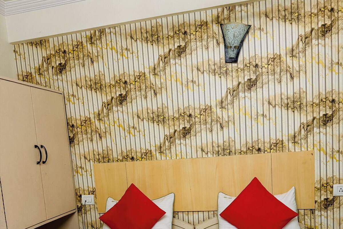 Une chambre d’hôtel avec un lit, deux oreillers rouges, une serviette blanche et une tête de lit en bois.