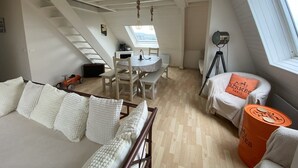 Una habitación estilo loft con comedor, cama con ropa blanca, un telescopio y ventana con vista.