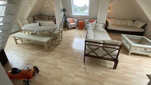 Un apartamento estilo loft con techo alto, una mesa de comedor con sillas, un sofá, una cama y una mesita de noche con lámpara.