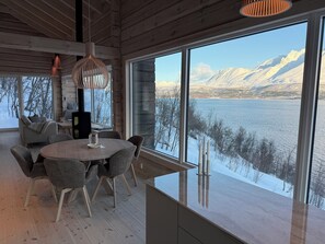 A modern interior with a large window offering a view of a lake and mountains.