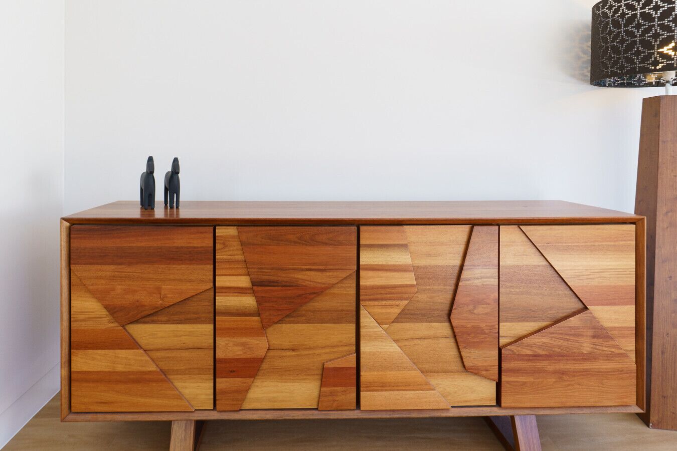 Un mobile in legno con motivi geometrici e due figurine sulla sommità.