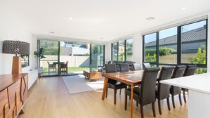 A modern kitchen with a dining area, large windows, and a view of the backyard.