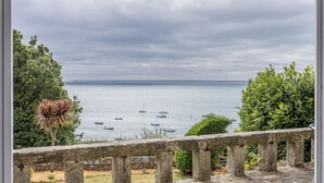 Blick auf die Küste mit Booten, einem Steg und viel Grün.