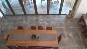 A dining area with a wooden table and chairs, a plant on the table, and a view through large glass doors to an outdoor patio. - Private farmhouse in the bush with AC, just outside Windhoek on a game farm. (Windhoek)