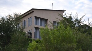 A modern building with a flat roof, large windows, and a flagpole. - Private farmhouse in the bush with AC, just outside Windhoek on a game farm. (Windhoek)
