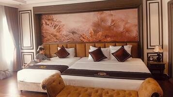 A hotel room with a large bed, two pillows, a headboard, a nightstand, a lamp, and a large floral wall mural.